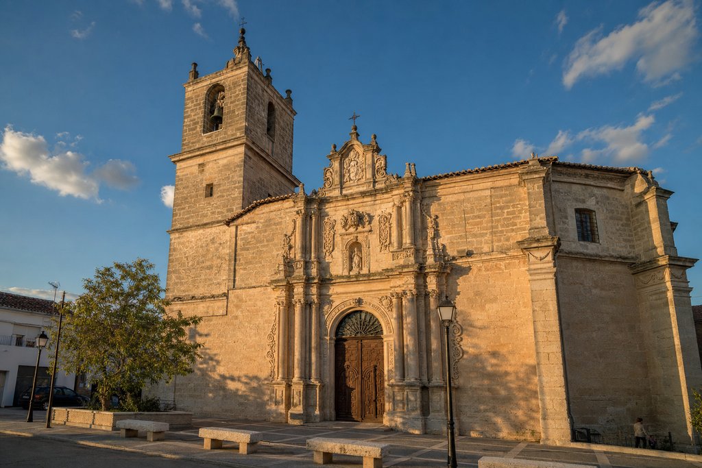 The Baroque bell tower and facade of Valdemoro's historic parish church in warm afternoon light